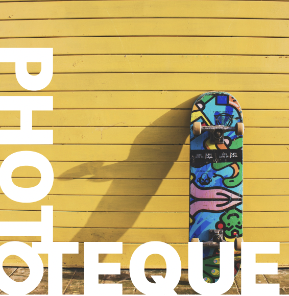 Planche de skateboard posée contre un mur avec un texte annonçant la phototèque